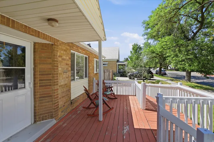 Covered front porch featuring a red-stained wooden deck and white wood railing