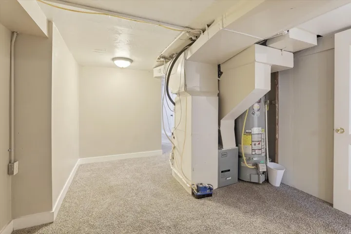 Utility area featuring a water heater, furnace, and exposed ductwork