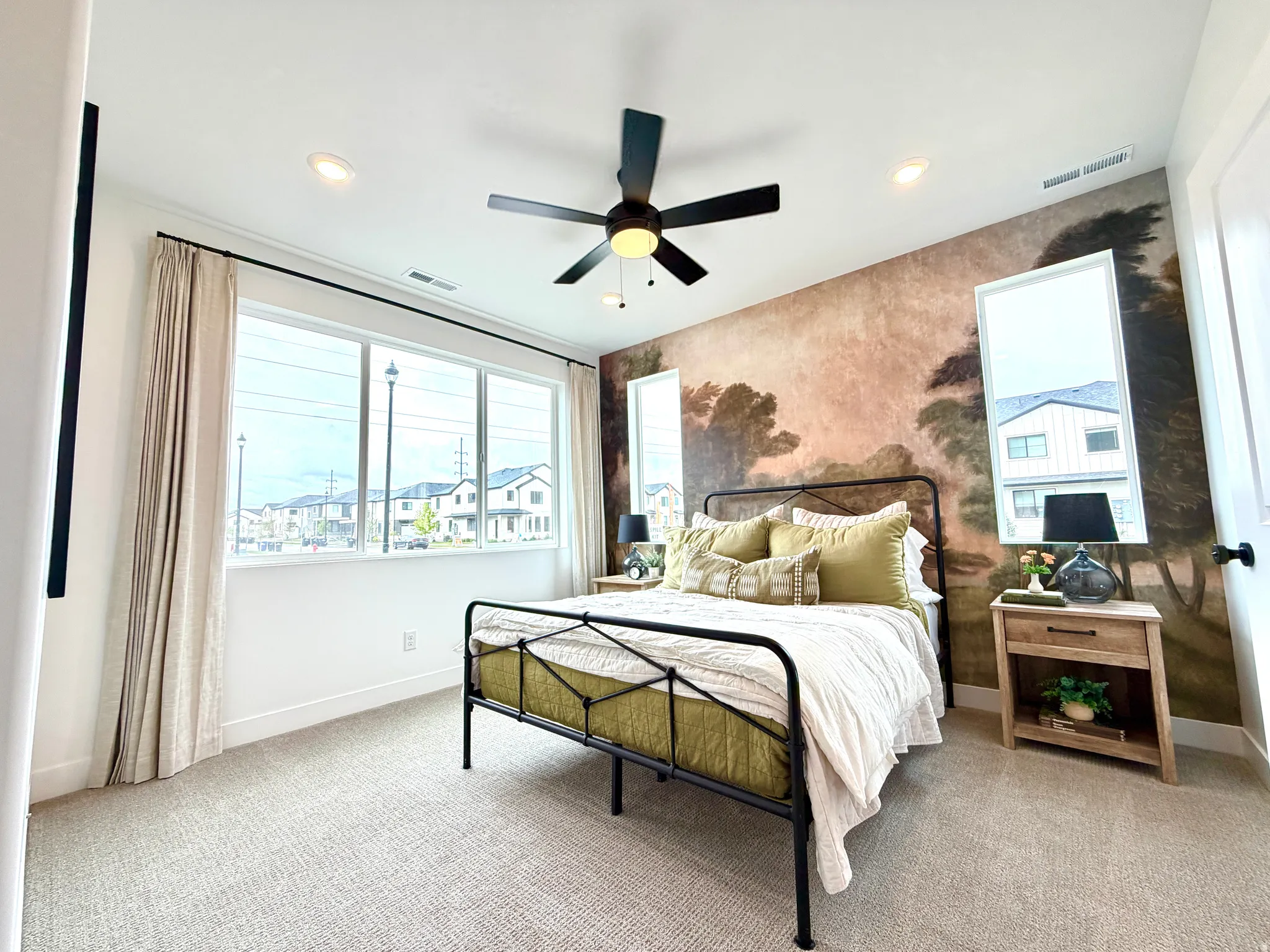 Bedroom with a feature wall showcasing a scenic mural, complemented by a large multi-pane window with white trim