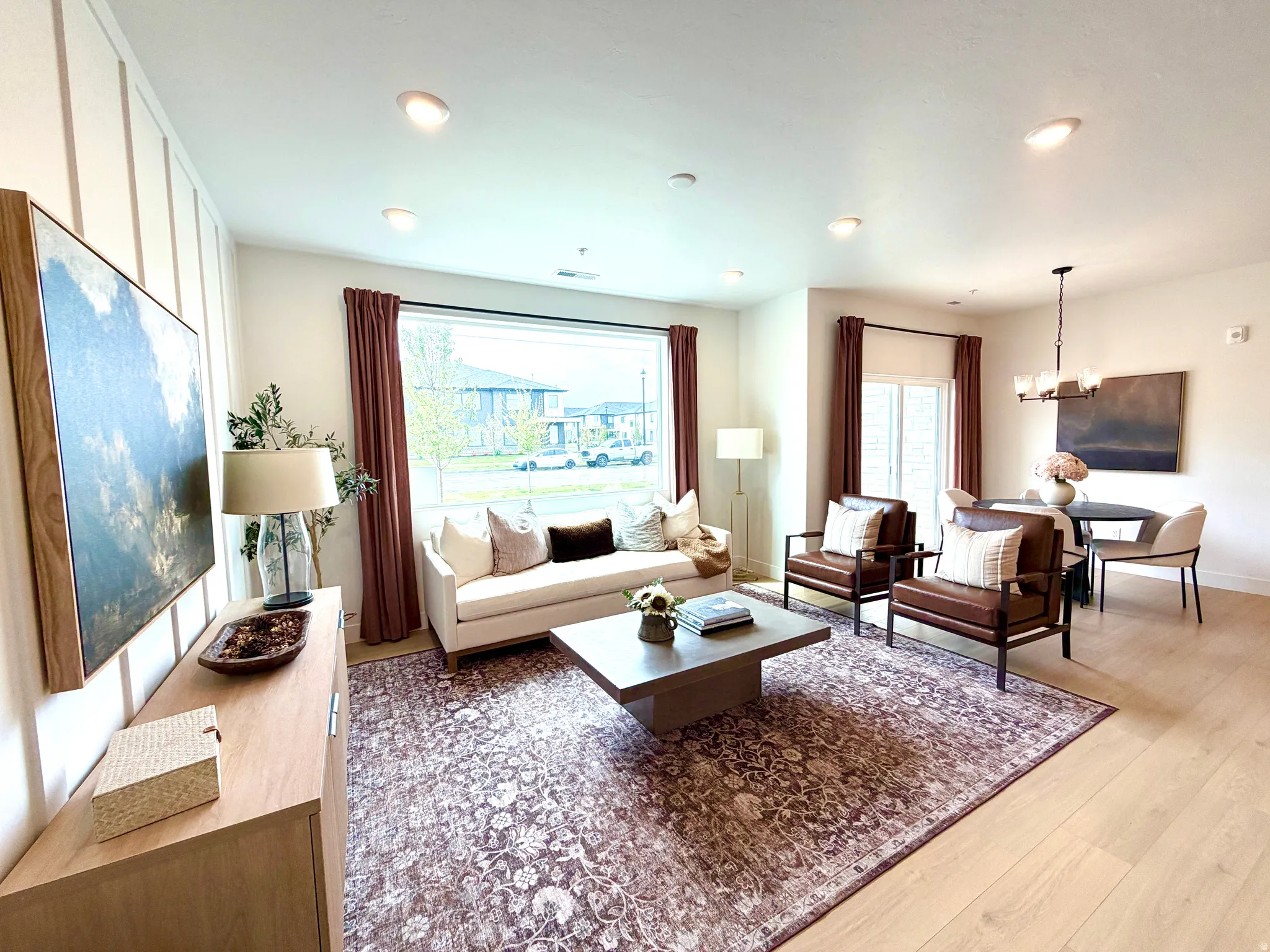 Open-concept living area featuring a prominent picture window, recessed lighting, and light wood-finish flooring