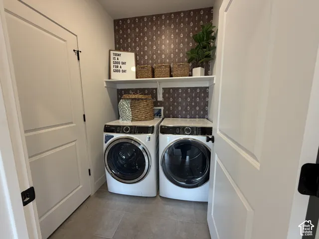 Laundry area featuring tile flooring, white shelving, and accent wall with patterned wallpaper