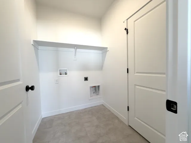 Dedicated laundry area featuring a built-in shelf, neutral wall tones, and panel doors with contrasting hardware