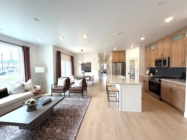 Open-concept living space featuring light wood-finish flooring, recessed lighting, and large windows
