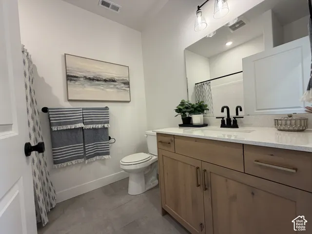 Bathroom featuring a light wood-finish vanity with gold-tone hardware, a white countertop, and a matte black faucet