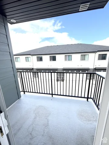 Balcony with textured flooring, black metal railing, and recessed overhead lighting