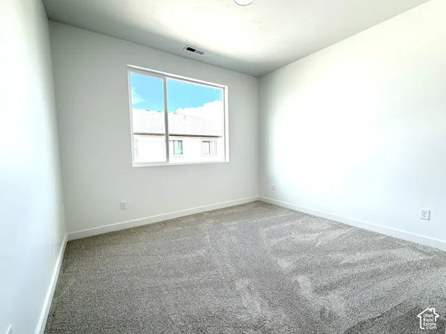 Wall-to-wall carpeting in a neutral tone, with crisp white walls and a large window