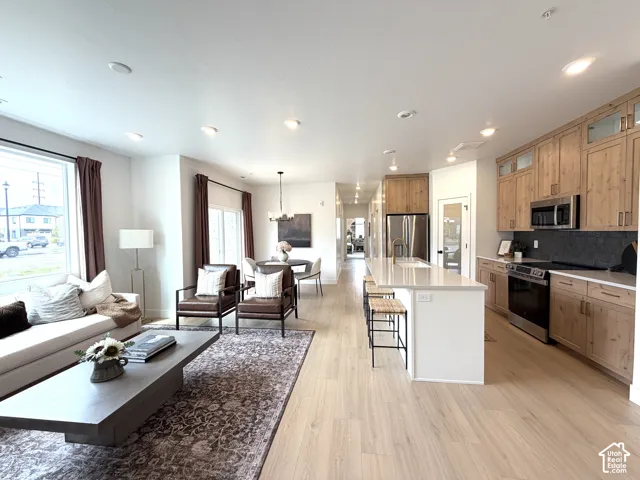 Open-concept living space featuring light wood-finish flooring, recessed lighting, and large windows