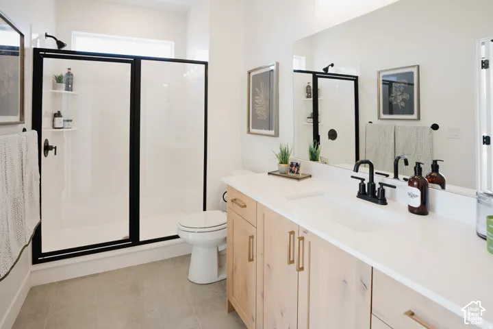 Bathroom featuring a light wood-finish vanity with a single basin, white countertop, and matte black faucet