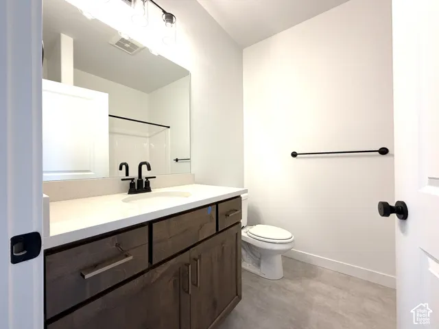 Full vanity with wood-finish cabinetry, light-toned countertop, and undermount sink