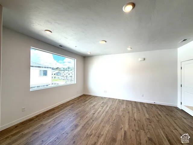 Expansive room featuring wood-finish flooring, recessed lighting, and a large horizontal window