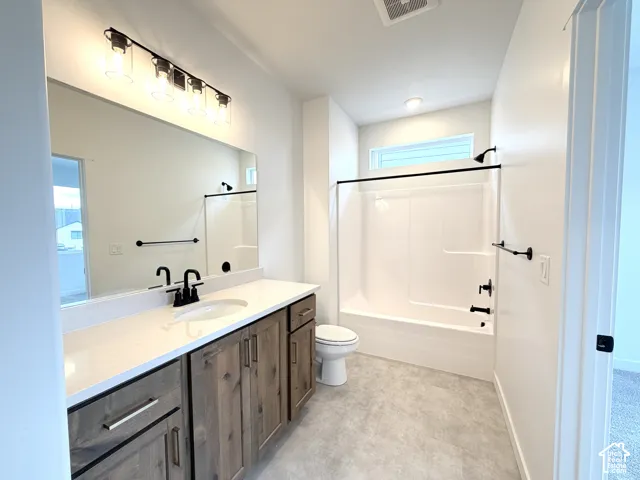 Bathroom featuring a single vanity with wood-finish cabinetry, solid surface countertop, and an integrated sink