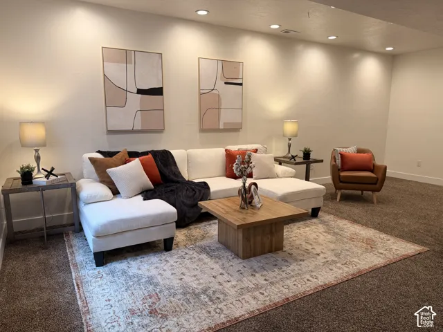 Recessed ceiling lighting illuminates a spacious room featuring a light-toned wall finish and brown carpeting