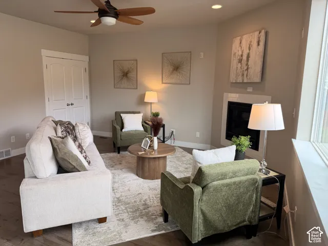 Recessed ceiling lighting, wood-finish flooring, ceiling fan with integrated light, fireplace with tile surround, and white trim accents