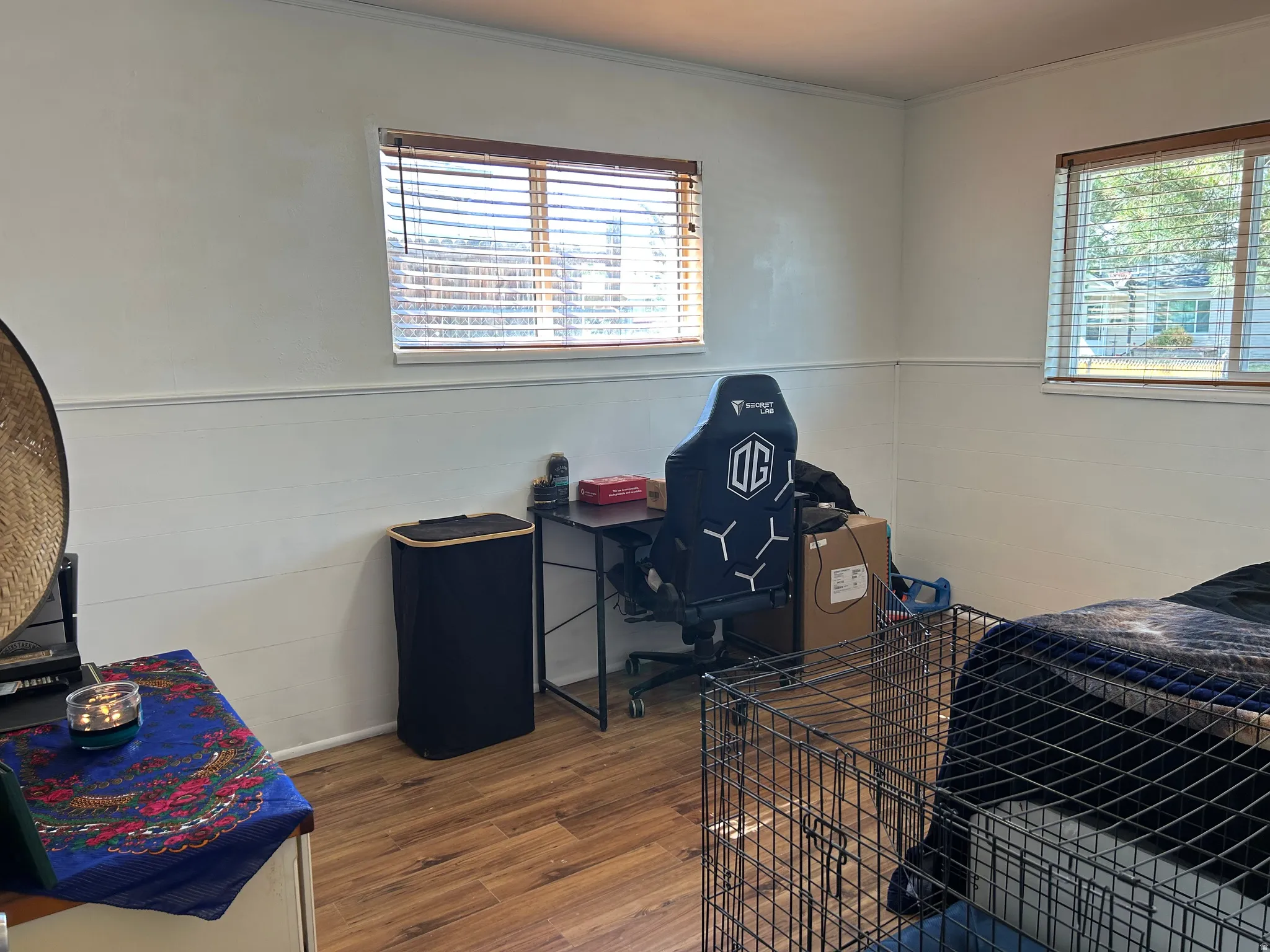Room featuring wood-finish flooring, white walls, and two windows with horizontal blinds