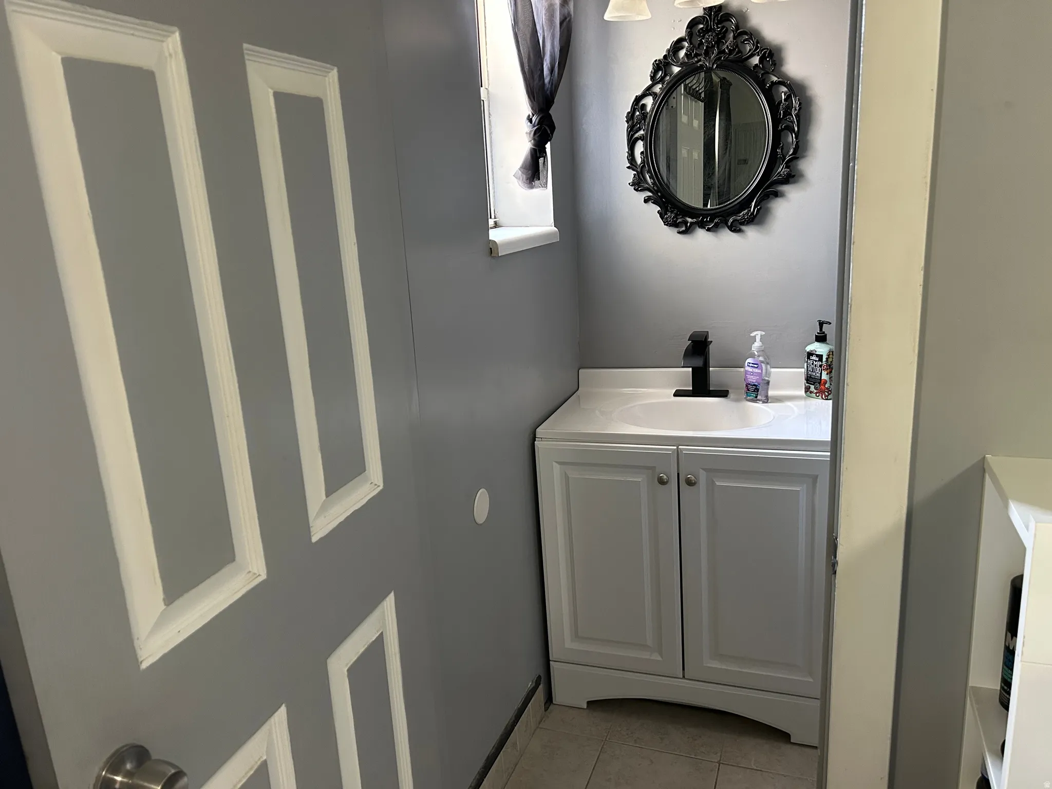 Compact vanity featuring a white cabinet, integrated sink, and black faucet