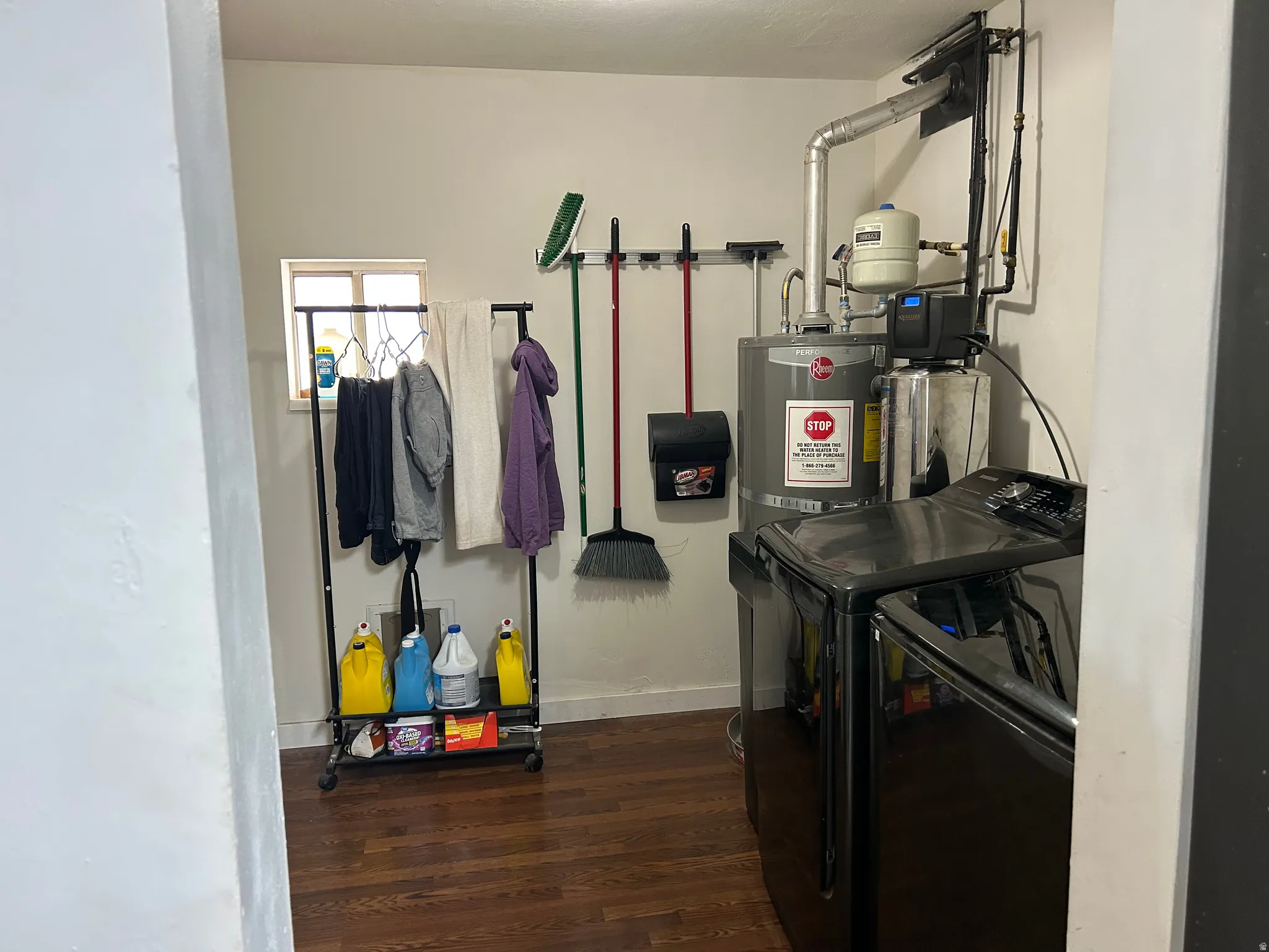 Dedicated laundry area featuring wood-finish flooring, a window providing natural light, and a water heater