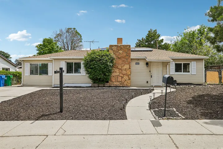 Ranch-style exterior with beige siding, stone-clad chimney, and a composite shingle roof
