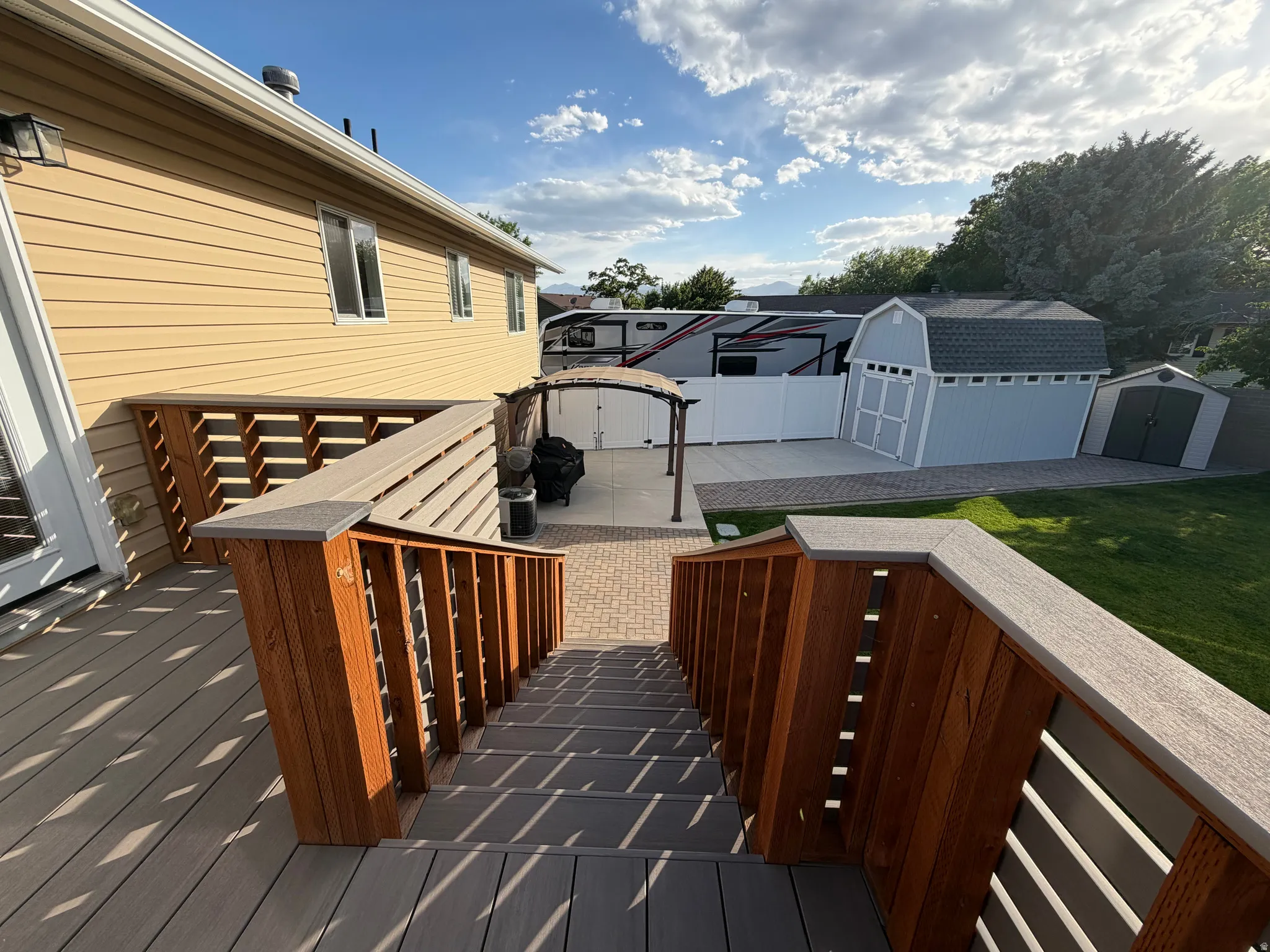 Spacious deck with composite decking and wood railings, leading to a paver patio