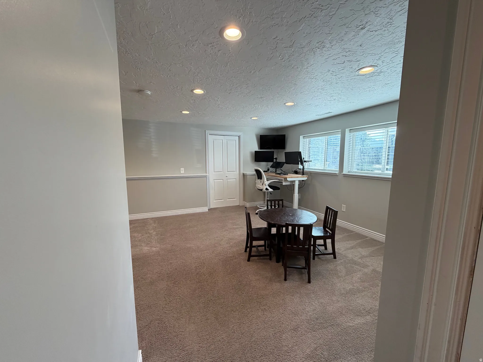 Open room featuring carpet flooring, recessed lighting, white baseboards, and two windows with blinds