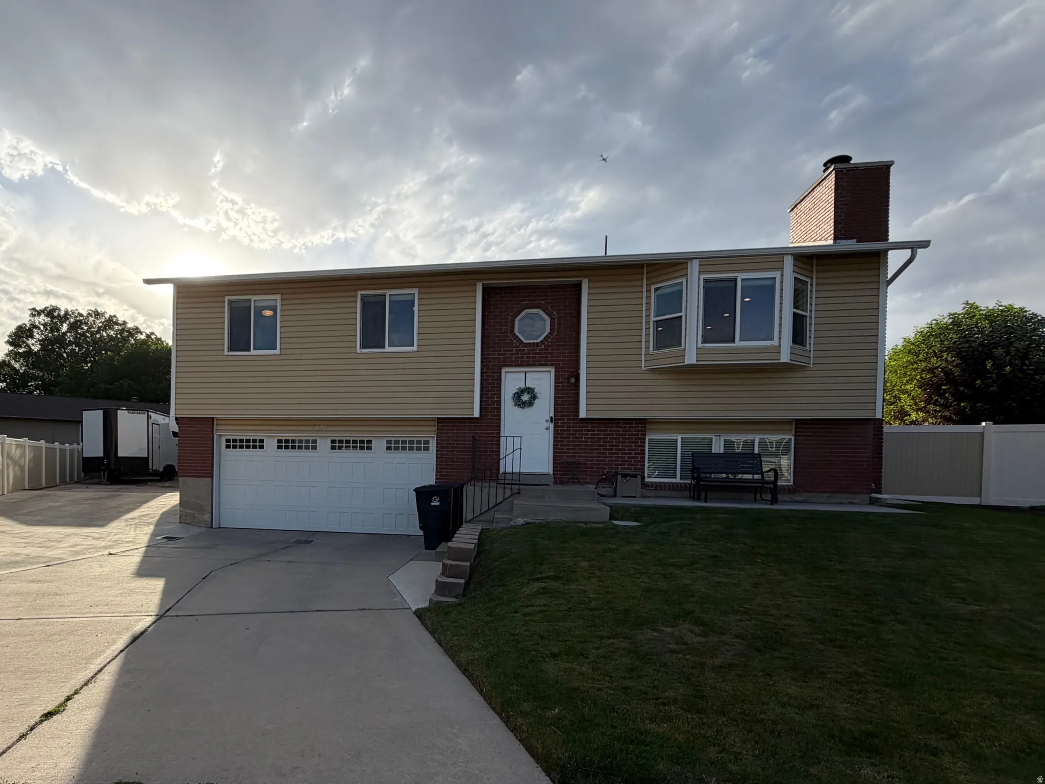 Split-level residence featuring a two-car garage, bay window, and a circular window accent