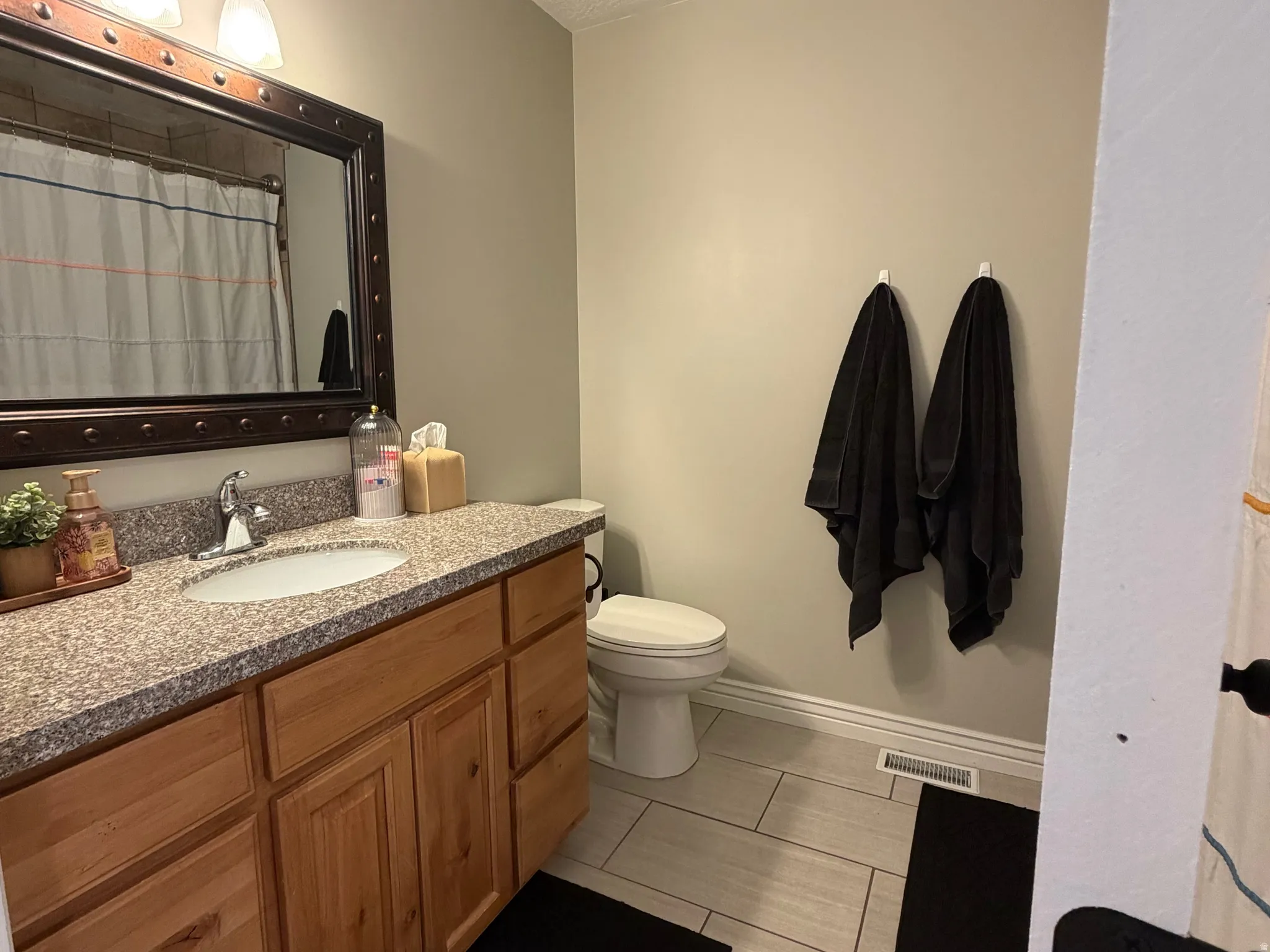 Bathroom featuring a wood vanity with a granite-style countertop and an undermount sink