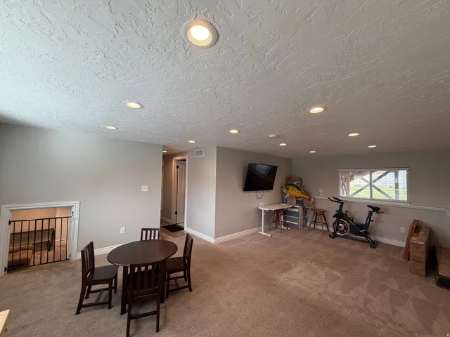 Spacious carpeted room featuring recessed lighting, a neutral paint palette, and a visible window allowing natural light