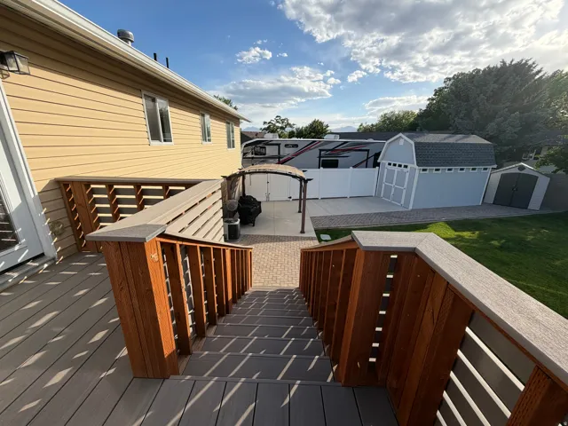 Spacious deck with composite decking and wood railings, leading to a paver patio