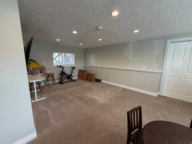 Spacious room featuring neutral carpeting, recessed lighting, and a window with natural light