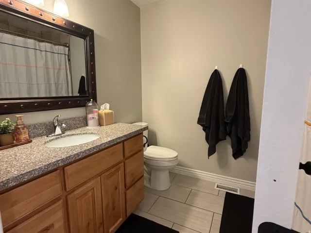 Bathroom featuring a wood vanity with a granite-style countertop and an undermount sink