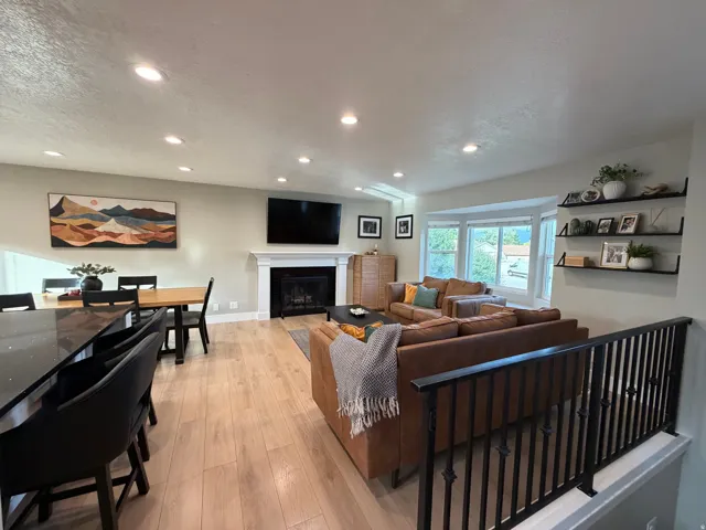 Open-concept living area featuring wood-finish flooring, recessed lighting, and a white fireplace mantel