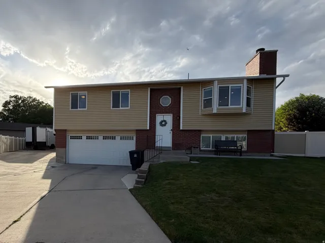 Split-level residence featuring a two-car garage, bay window, and a circular window accent