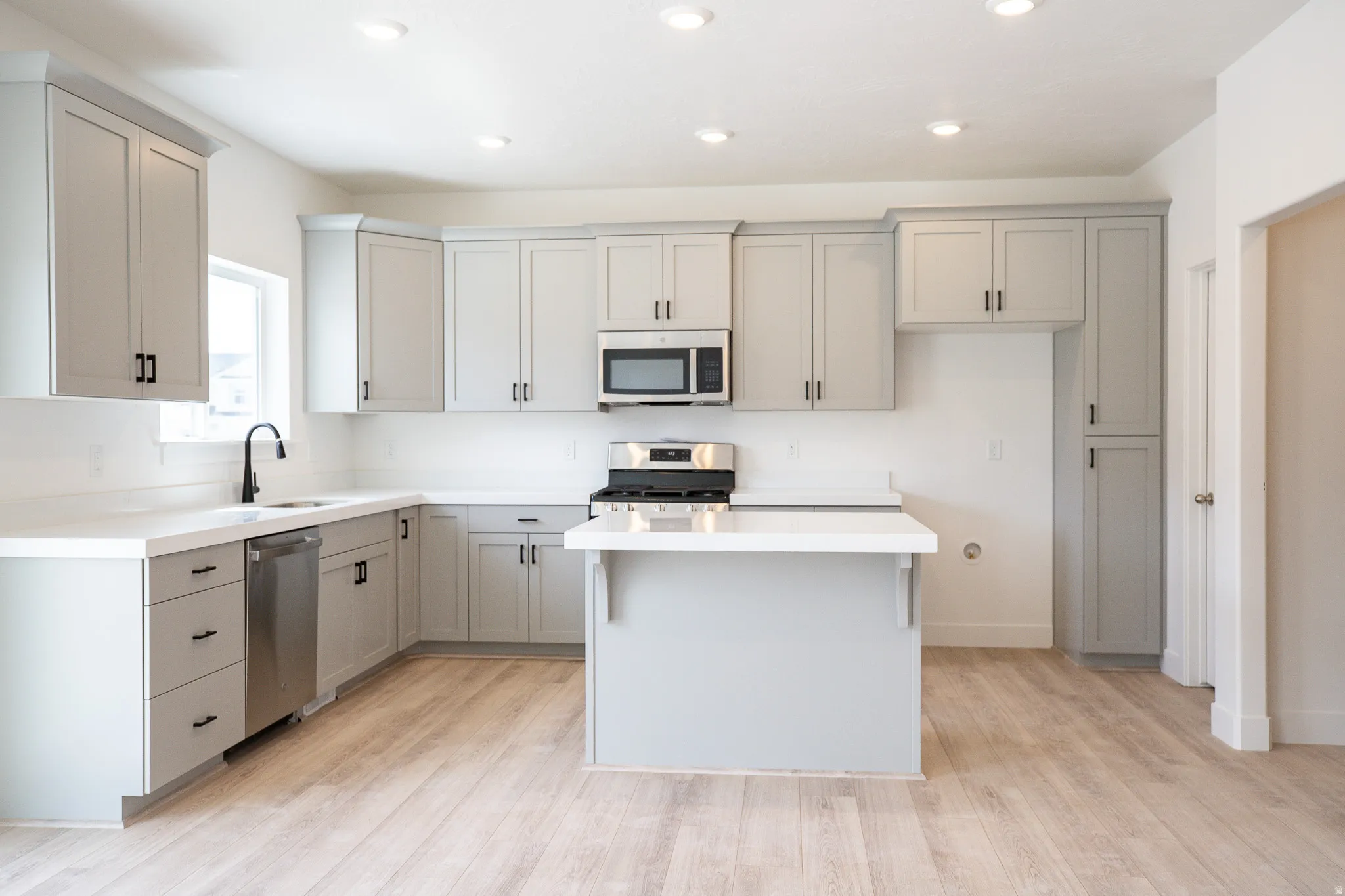 Great kitchen with painted wood cabinets, 42" uppers, quartz slab countertops, gas range, microwave, dishwasher and disposal.