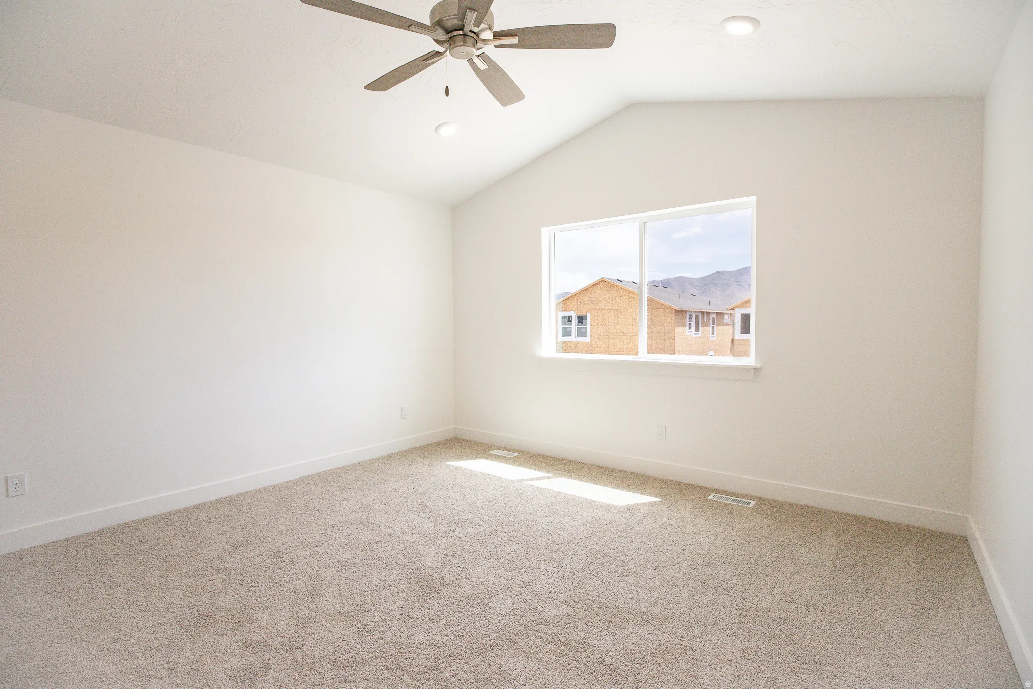 Large primary bedroom with vaulted ceiling, ceiling fan and large walk-in closet as part of primary suite.
