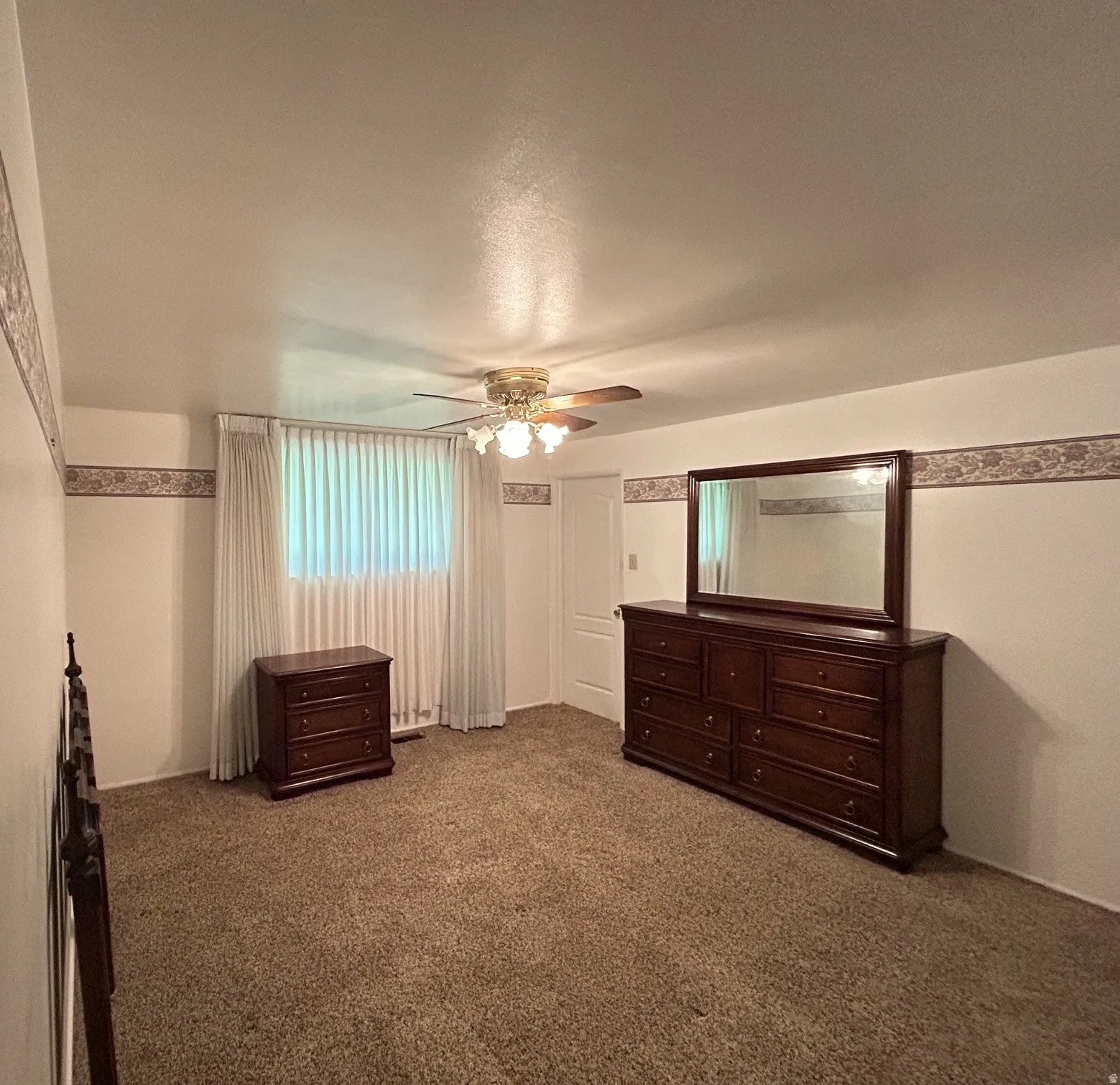 Main bedroom featuring a ceiling fan with integrated lighting, a window with vertical blinds & an access door to 1/2 bath.