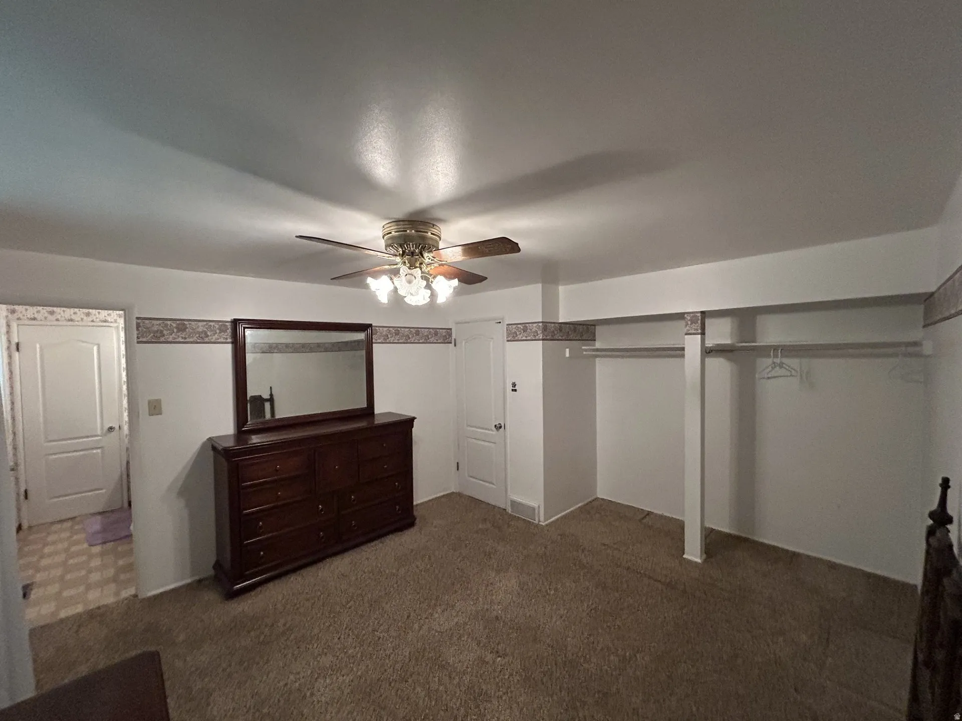 Main bedroom featuring neutral tone carpet flooring, a ceiling fan light fixture & access door to 1/2 bath.