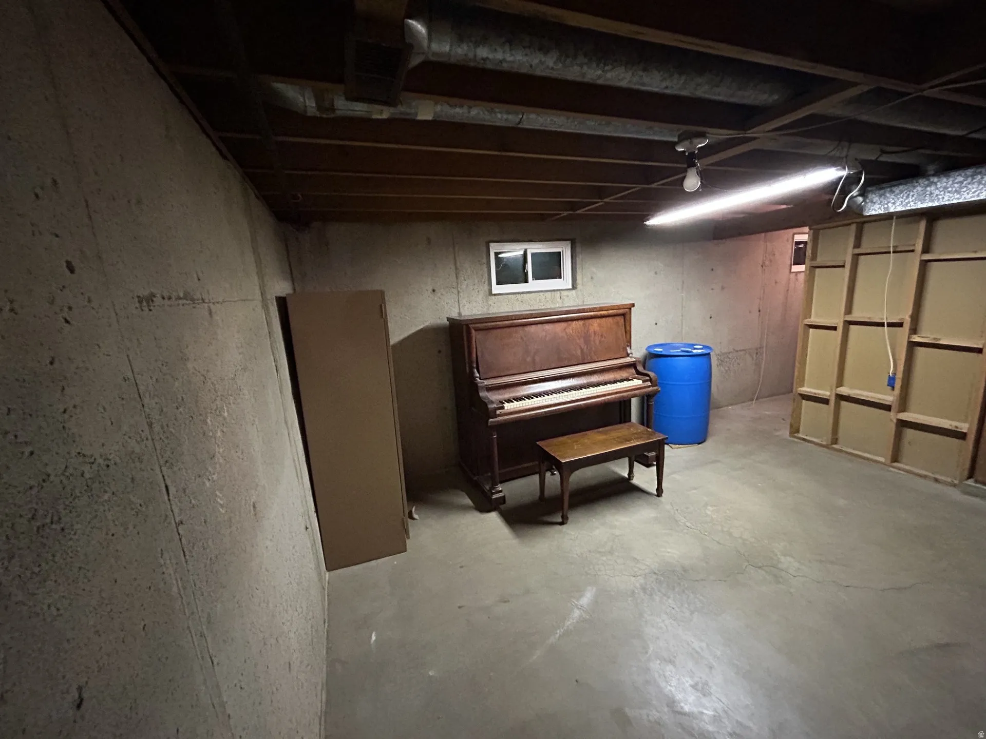 Unfinished basement featuring concrete slab flooring & ceiling joists access
