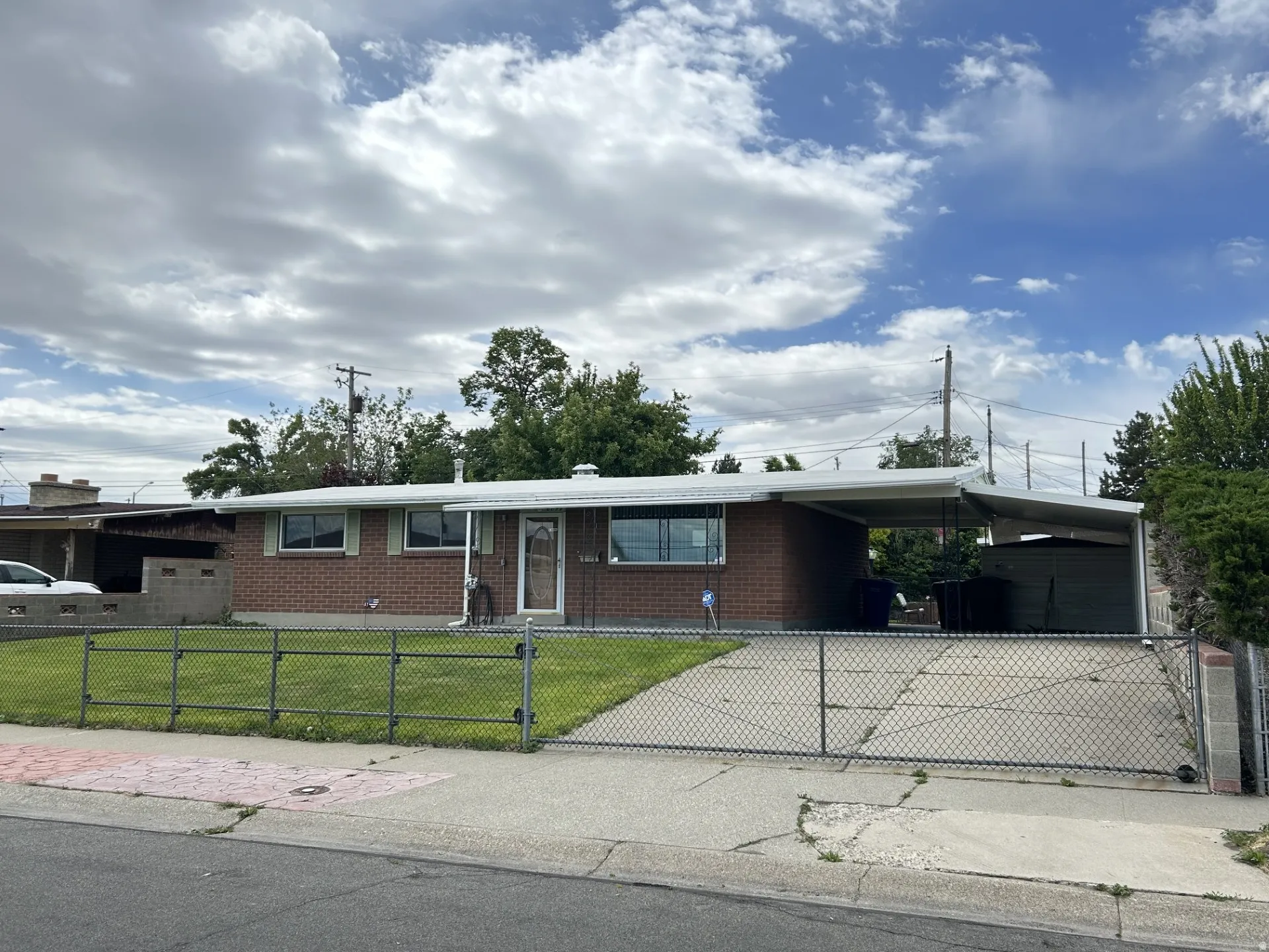 Brick rambler home with a covered carport & extended length driveway for parking.
