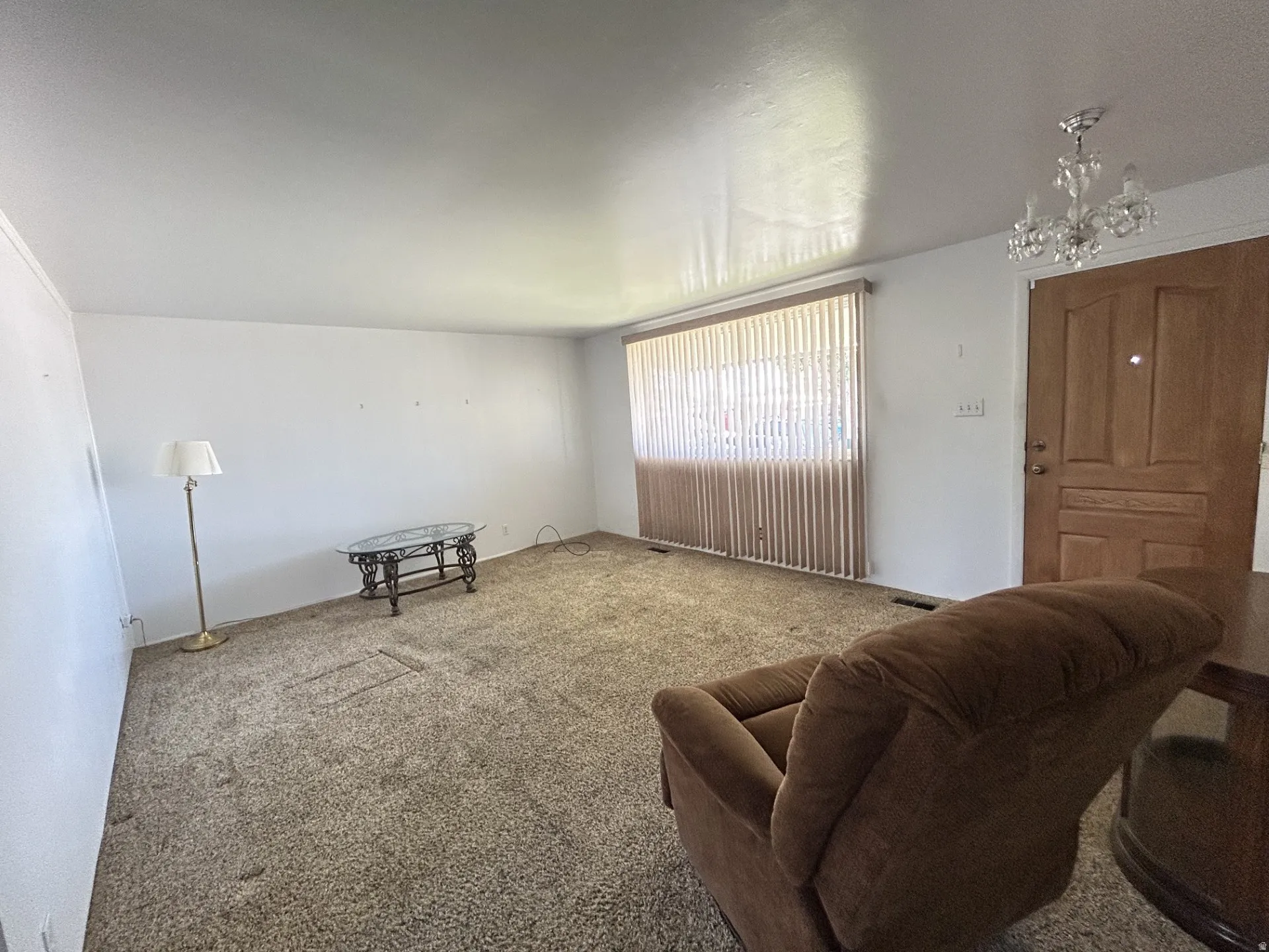 View from the hallway off this room that has white walls & a large window with vertical blinds