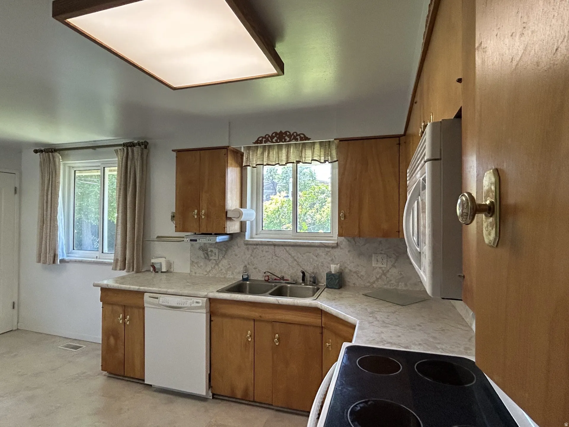 Kitchen featuring wood cabinetry, white appliances, a double basin sink, and ample counter space
