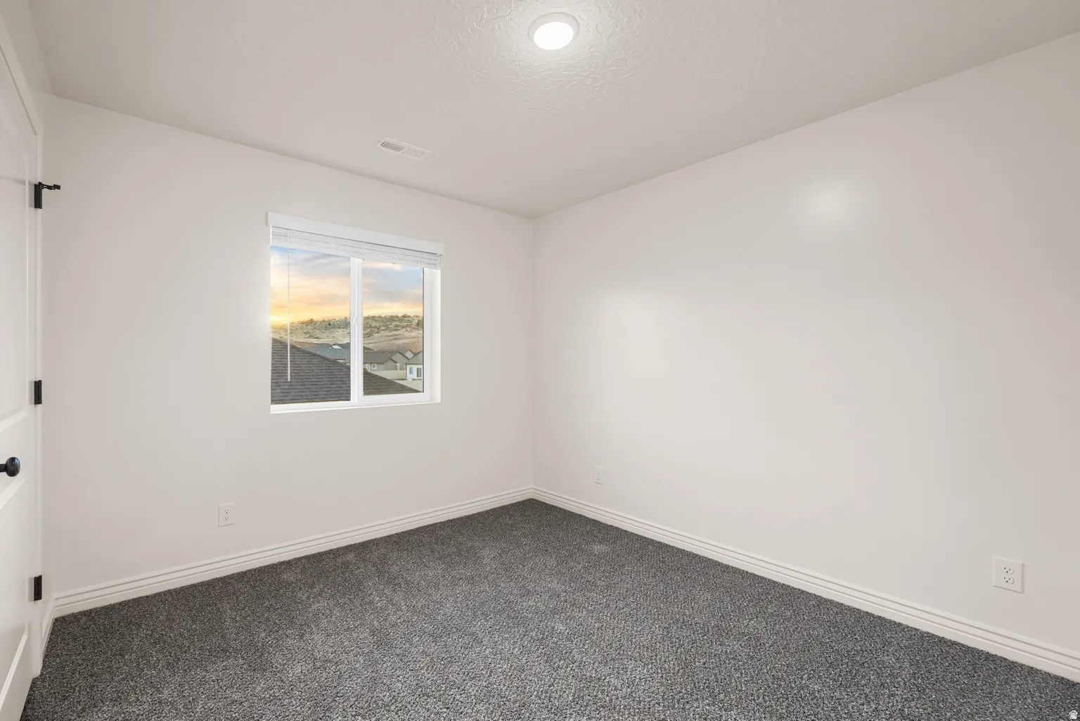 Neutral white walls complement the dark gray carpet