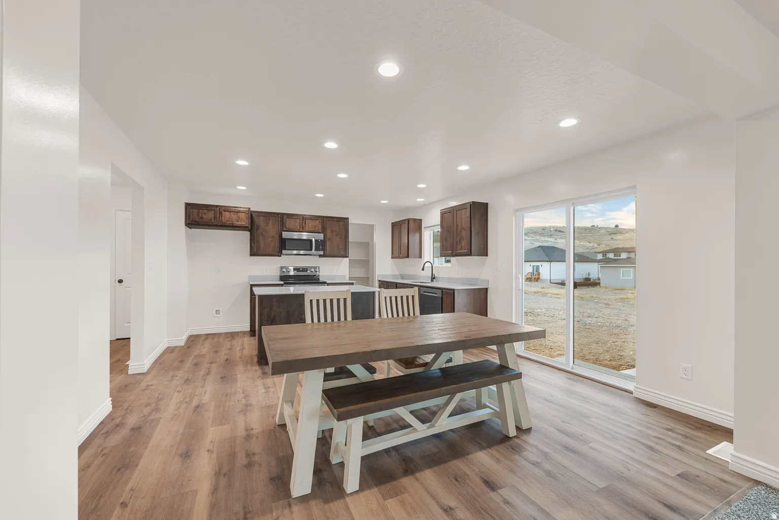 Open-concept kitchen and dining area featuring wood-finish flooring, recessed lighting, and white walls