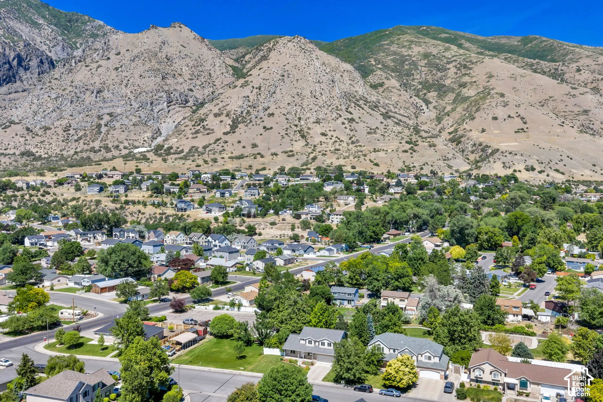 Aerial perspective showcasing a residential community nestled at the base of expansive, rugged mountains