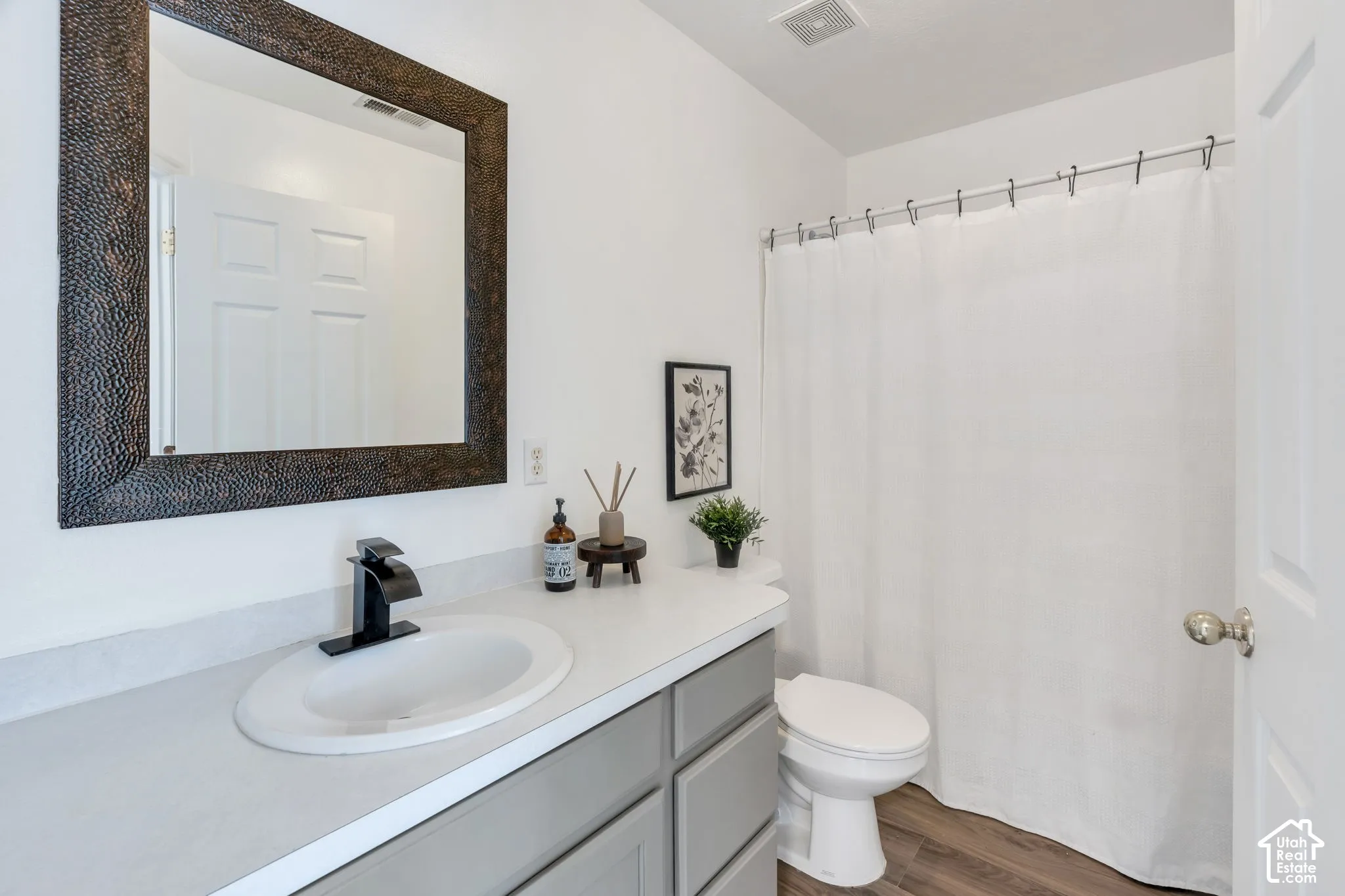 Bathroom featuring a single vanity with a white countertop, an oval undermount sink, and a matte black faucet