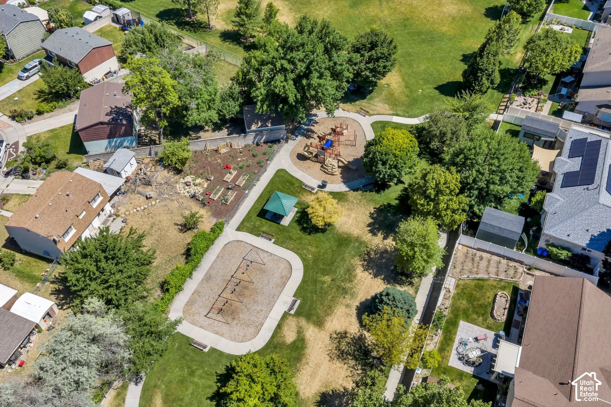 Expansive green space featuring a playground, walking paths, and mature trees