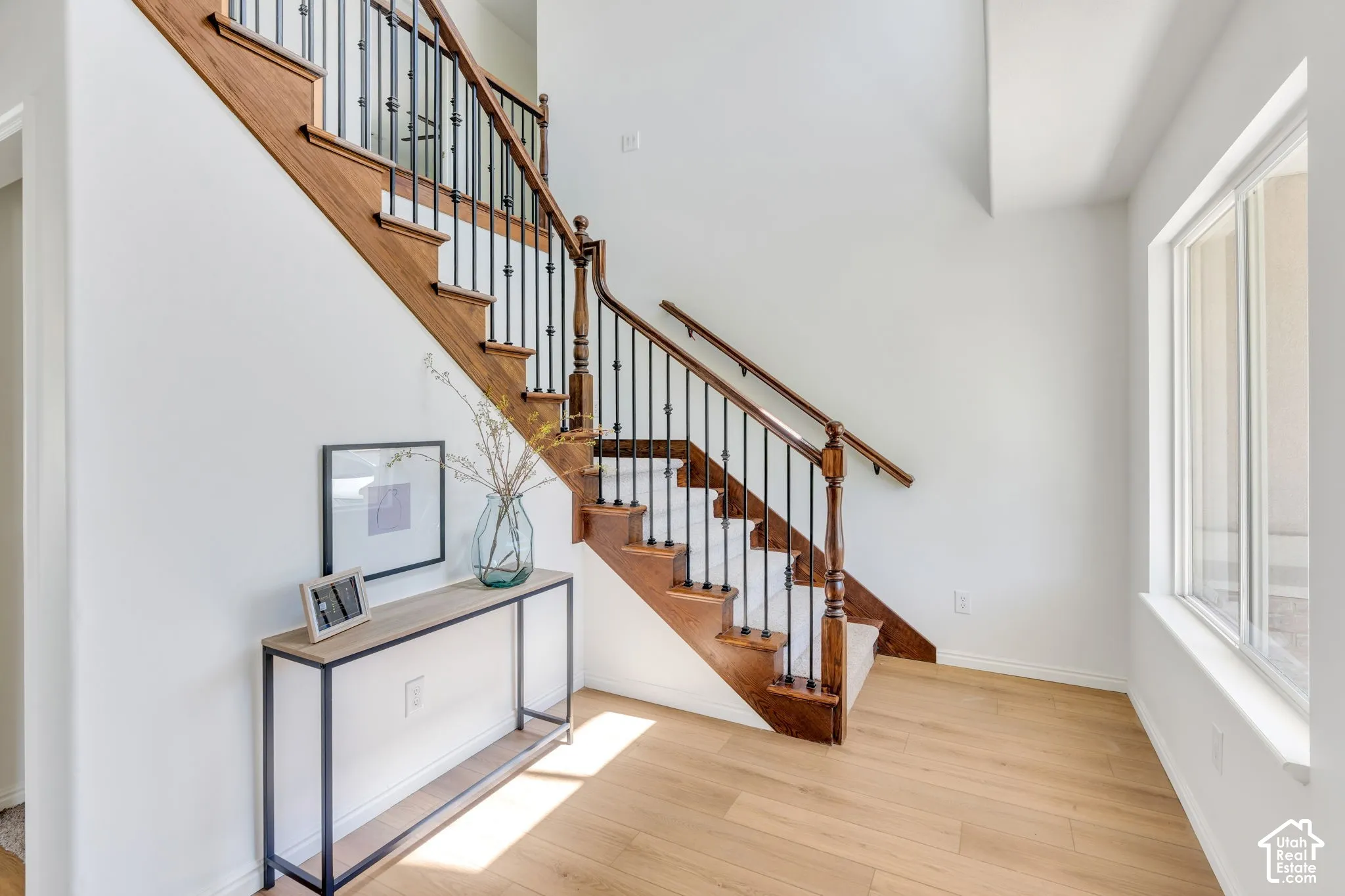 Grand staircase featuring dark wood newel posts, handrails, and balusters with wrought iron spindles