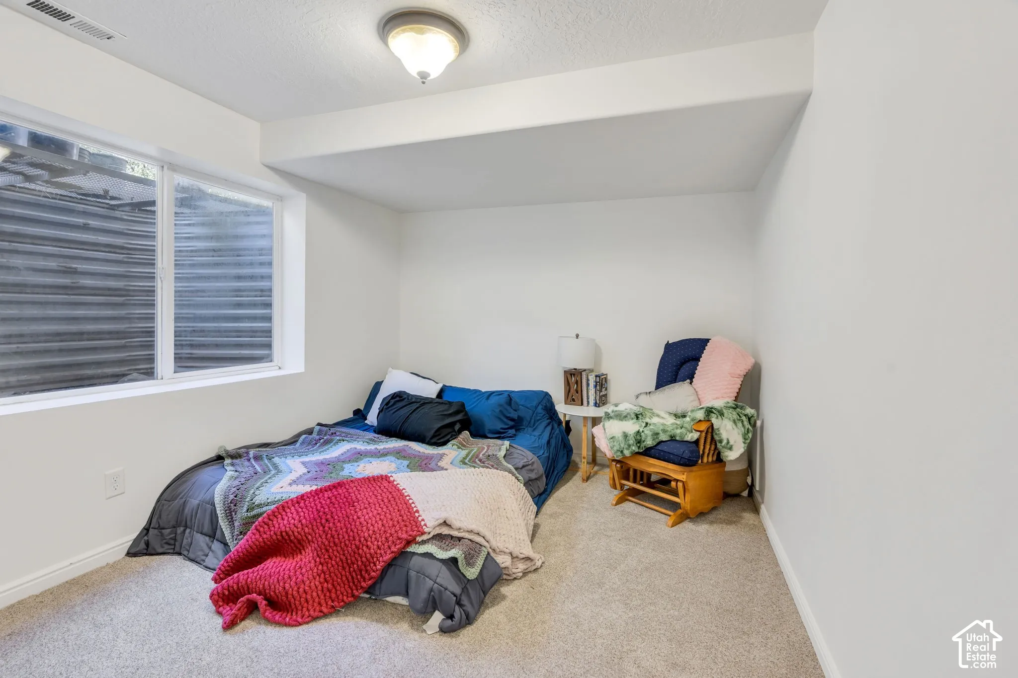 Light-filled room featuring a large egress window, neutral wall paint, and ceiling-mounted lighting