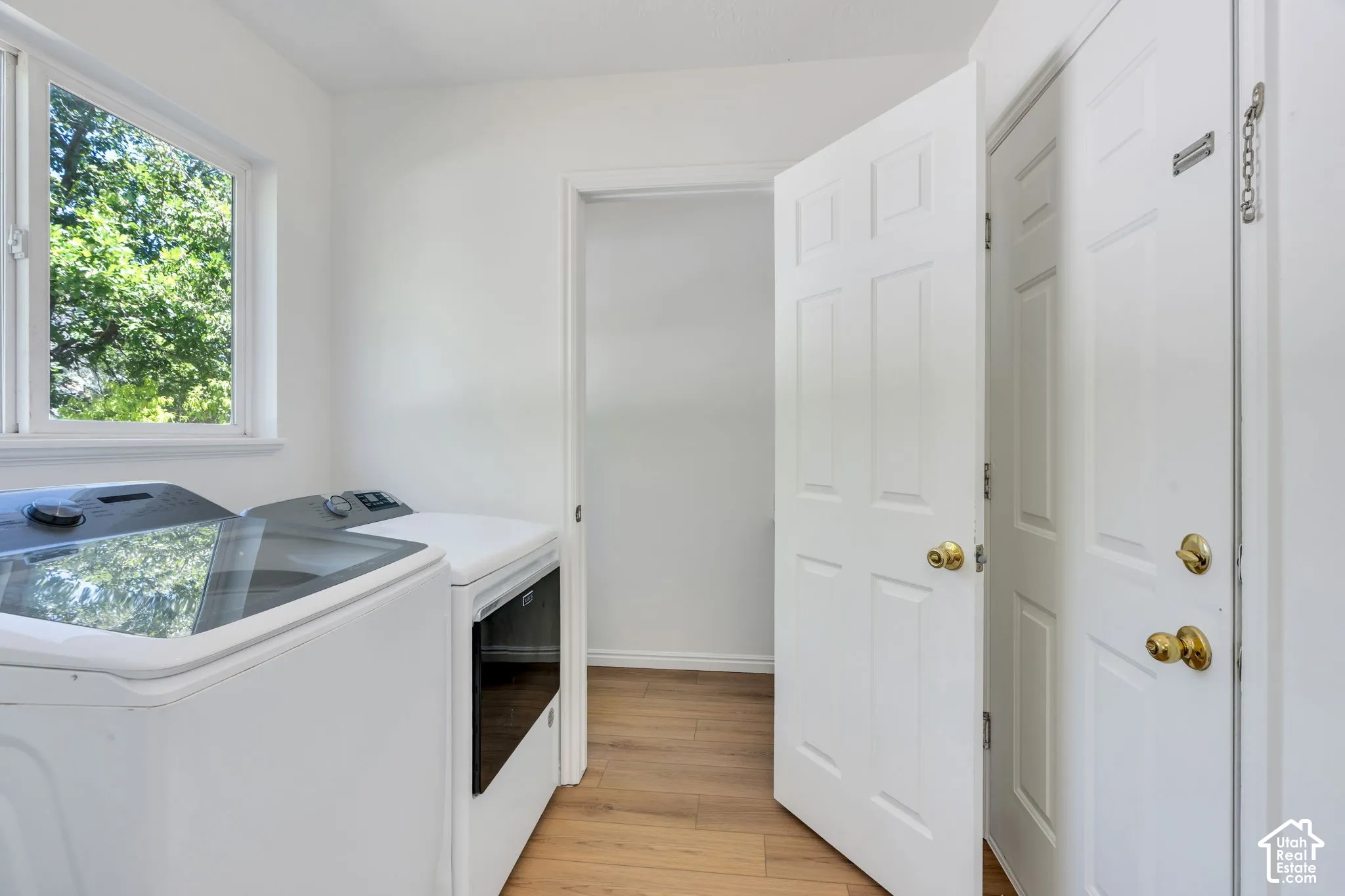 Laundry room featuring wood-finish flooring, a white window frame, and bright white walls