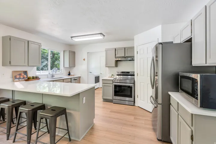 Modern kitchen featuring light wood-finish flooring, white countertops, and gray cabinetry