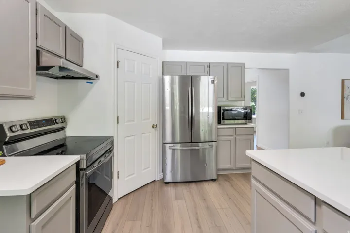 Kitchen featuring light wood-finish flooring, light gray cabinetry, white countertops, and stainless steel appliances