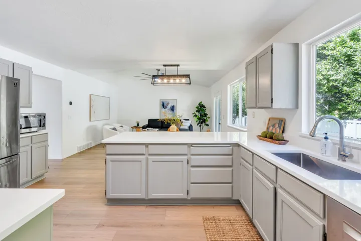 Kitchen featuring a large island with white countertops, light gray cabinetry, and wood-finish flooring